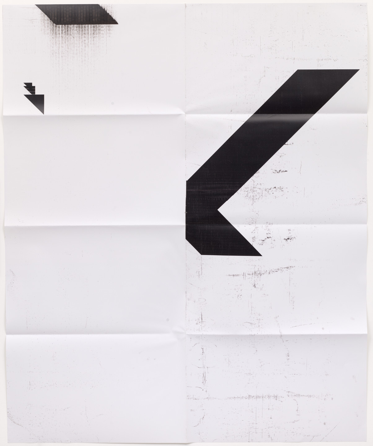 The image features a large, predominantly white paper with visible folds and creases. There are two prominent black geometric shapes: one in the upper left and a larger one forming a checkmark-like shape on the right side. This is an AI generated description. To give feedback, email ai@moma.org.