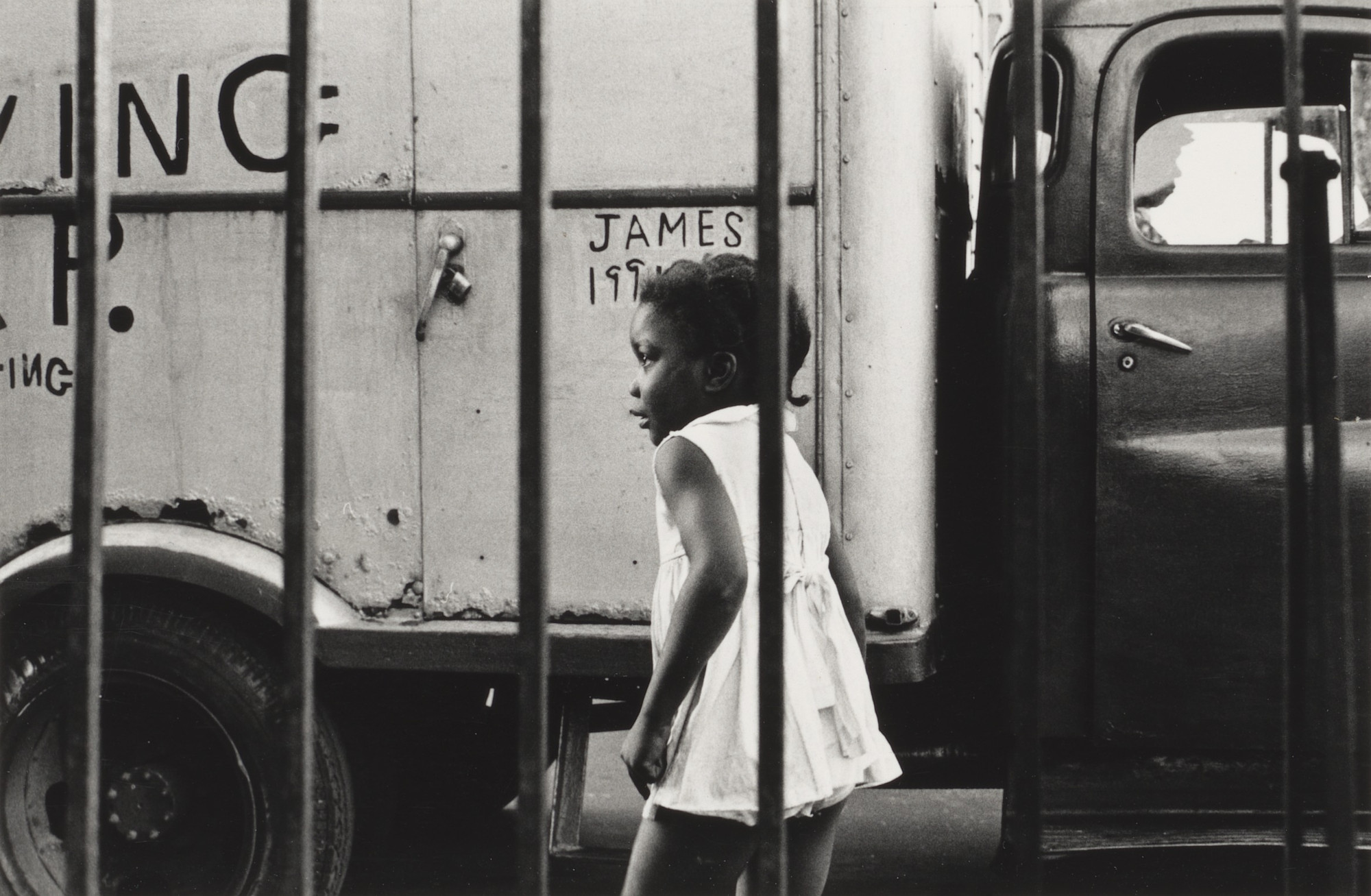 Shawn W. Walker. Young Girl in Front of Truck, 120th Street, Harlem, NY. 1962