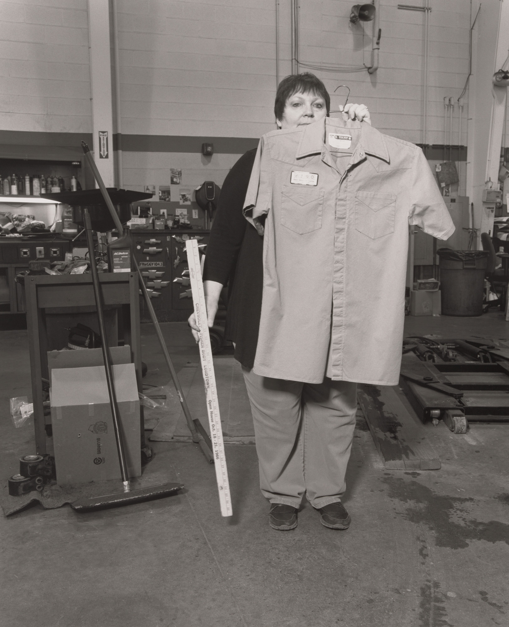 LaToya Ruby Frazier. Lisa Cartwright, Service Cashier, holding her father’s work shirt and his Chevro-let Fisher Body antique ruler, inside the maintenance shop at Sweeney Chevro-let Buick GMC car dealership, Board-man, OH