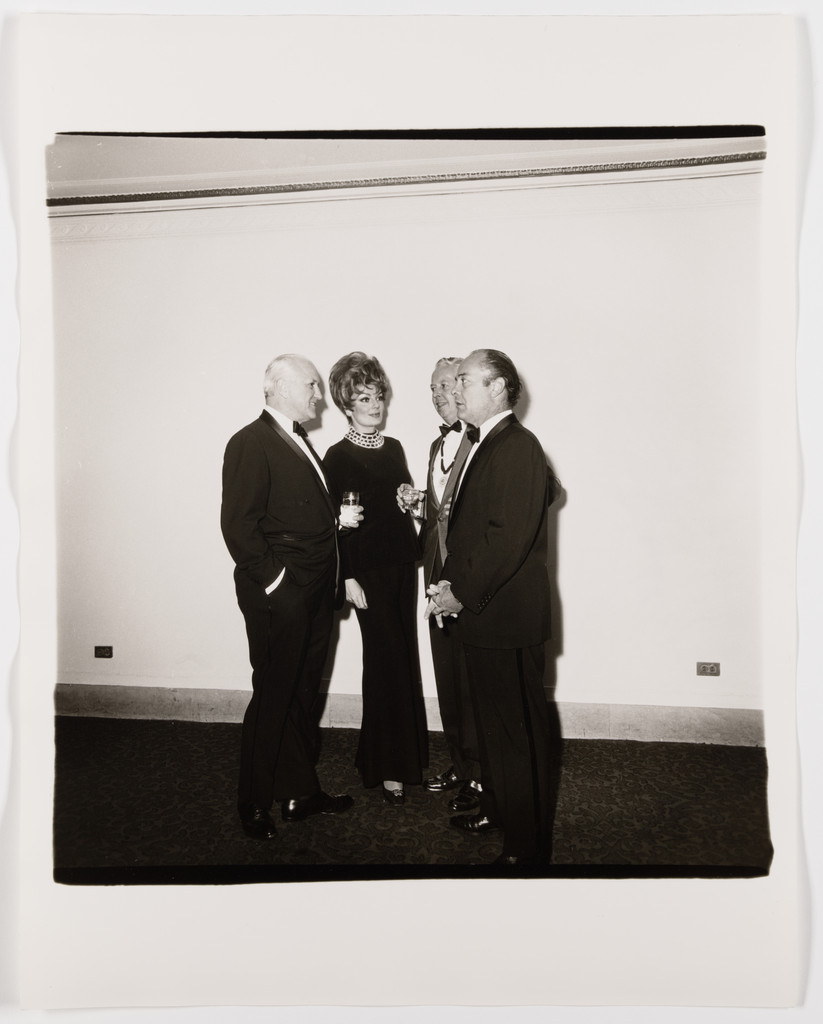 Four people in evening dress in conversation, 1968
