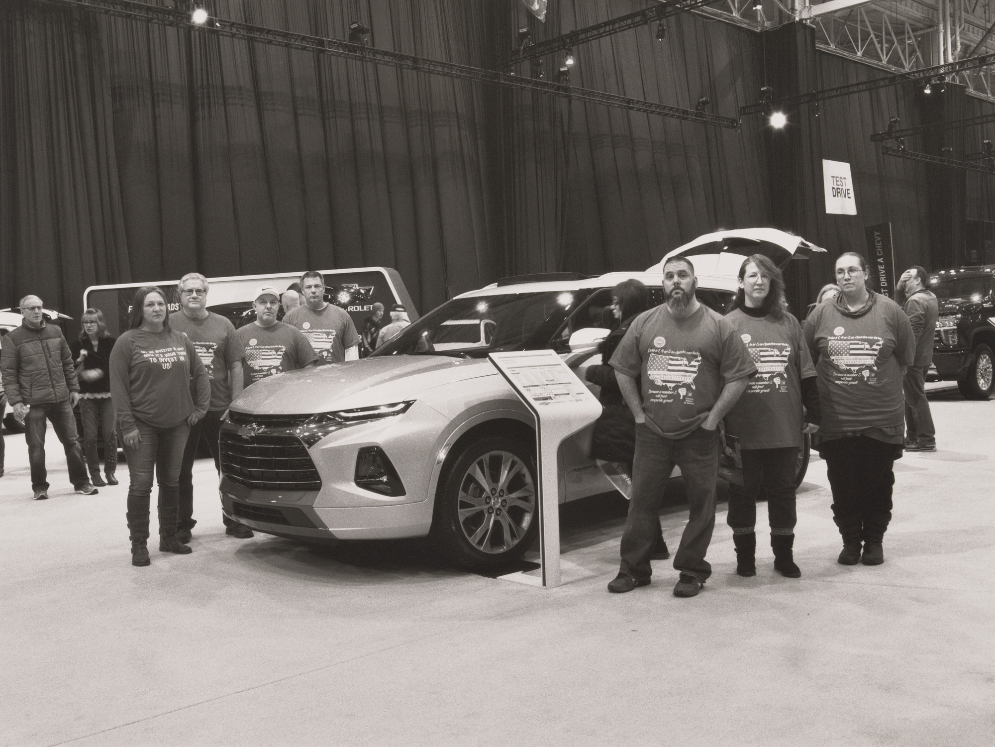 LaToya Ruby Frazier. United Auto Workers Casey Waldorf, Linda Fetchko, Jennifer Marlow, Kasey King, Timothy O’Hara, John Davies, and David Green in their VIN (vehicle identification number) t-shirts, standing next to a 2019 Chevrolet Blazer, midsize crossover SUV, built in Mexico, at the Cleveland Auto Show, Cleveland, OH, 2019