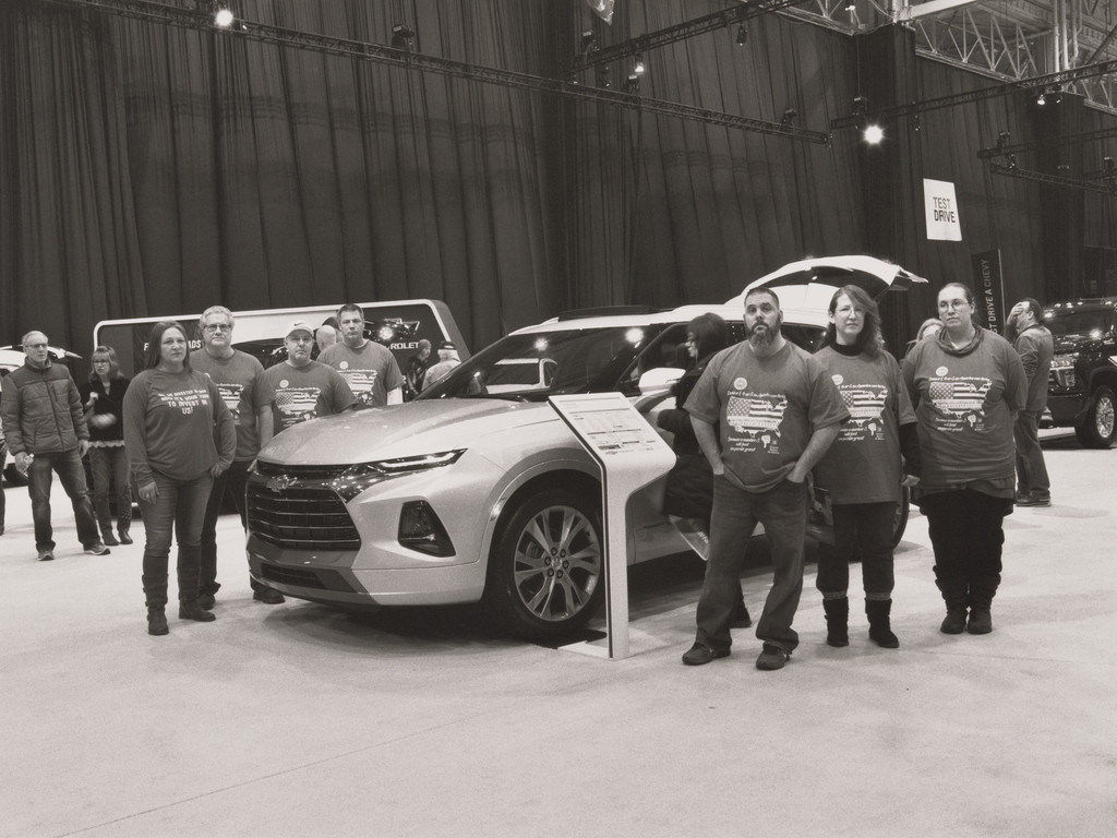 United Auto Workers Casey Waldorf, Linda Fetchko, Jennifer Marlow, Kasey King, Timothy O’Hara, John Davies, and David Green in their VIN (vehicle identification number) t-shirts, standing next to a 2019 Chevrolet Blazer, midsize crossover SUV, built in Mexico, at the Cleveland Auto Show, Cleveland, OH, 2019 from The Last Cruze