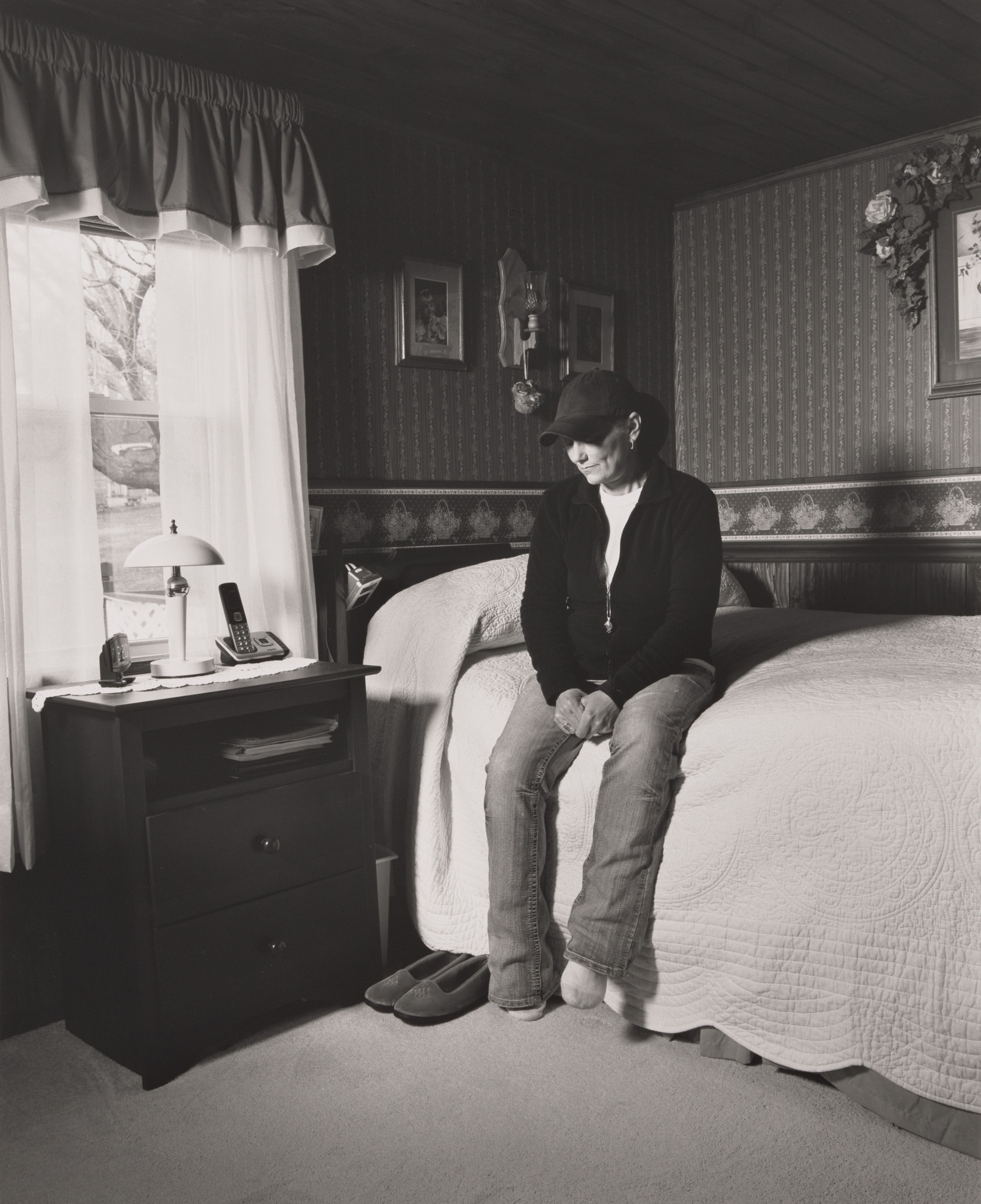 LaToya Ruby Frazier. Vickie Raymond, UAW Local 1112, sitting on her mother Margie’s bed in her bedroom, (24 years in at GM Lordstown Complex, trim and paint shop), East Rochester, OH.