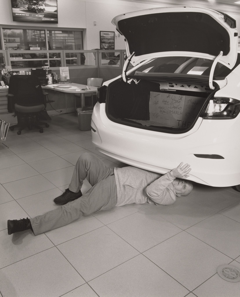 Keith Burke, Sales and Leasing Specialist, looking for hidden signatures left near the chassis and frame underneath the last Cruze by the United Auto Workers, Sweeney Chevrolet Buick GMC car dealership, Boardman, OH.