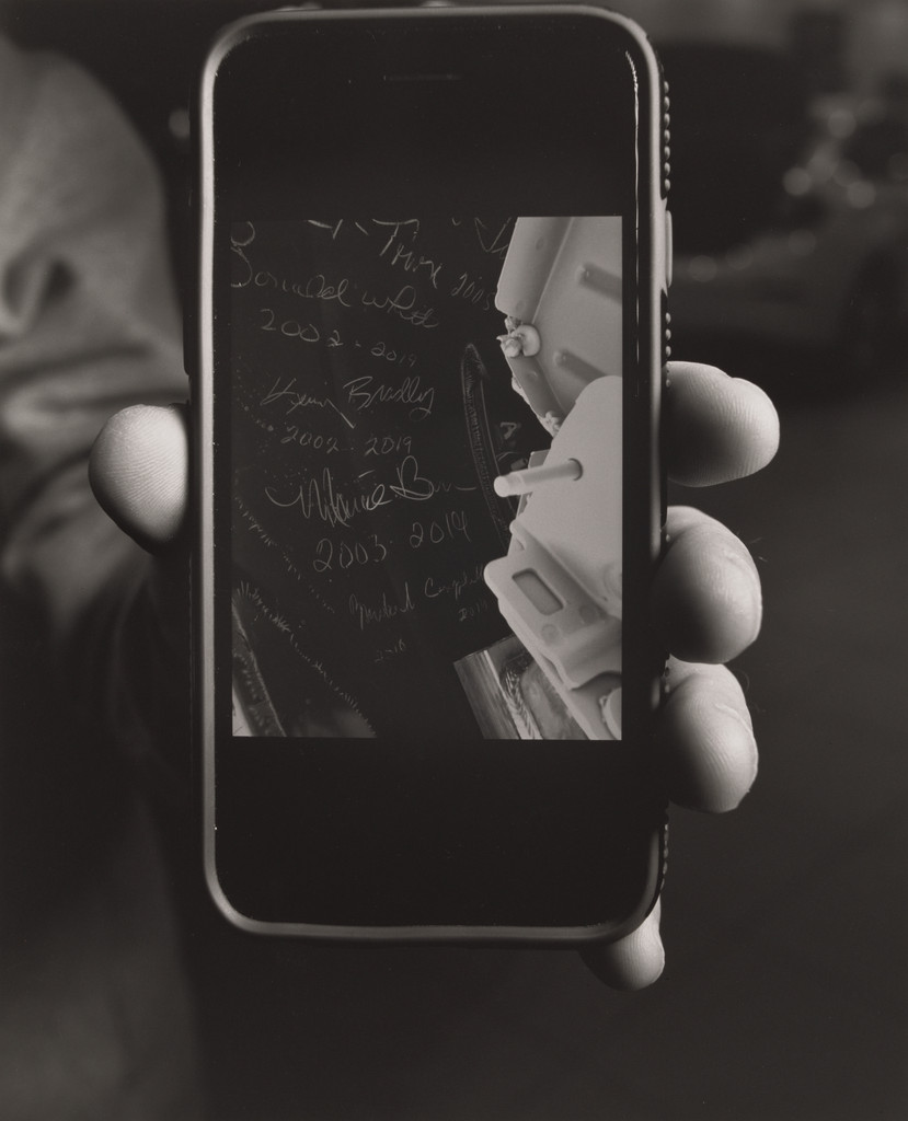 Keith Burke, Sales and Leasing special-ist, showing his cellphone photo of hidden signatures left near the chassis and frame of the last Cruze by the United Auto Workers, Sweeney Chev-rolet Buick GMC car dealership, Boardman, OH.