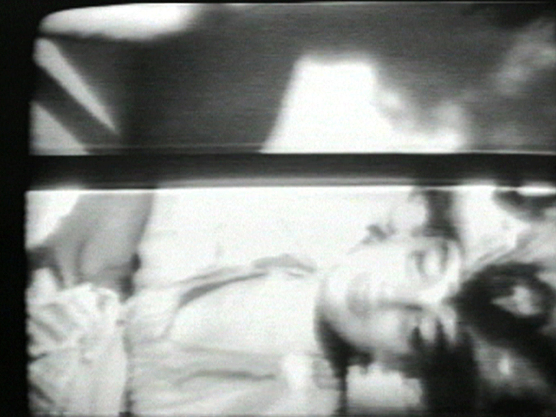The image is a black and white photograph showing a blurred face with closed eyes, seemingly in a restful pose. Shadows and light effects create areas of high contrast across the image. This is an AI generated description. To give feedback, email ai@moma.org.