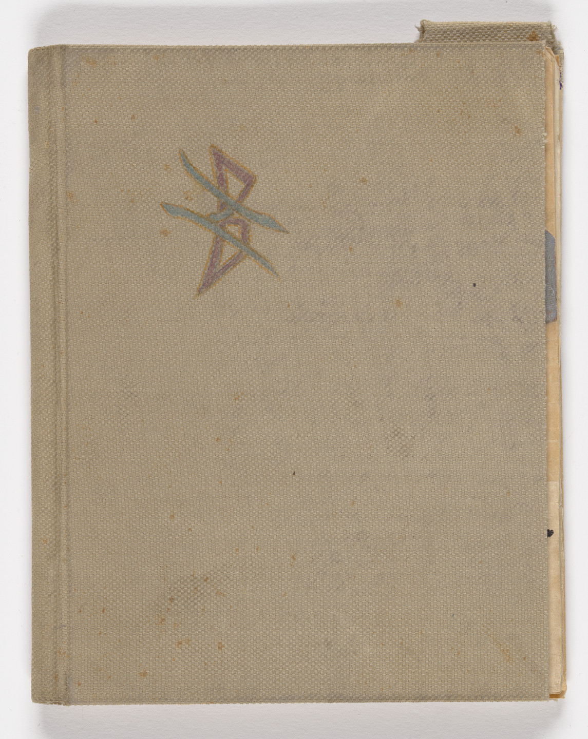 The image depicts a closed, beige-colored book with a small, multicolored geometric design in the top left corner. The cover appears slightly worn with some spots and fraying at the corner. This is an AI generated description. To give feedback, email ai@moma.org.