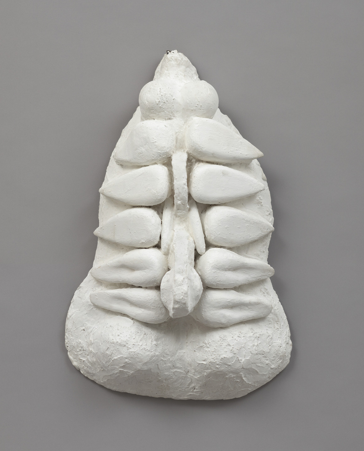 The image shows a textured white plaster sculpture with a rounded, layered, and symmetrical design on a gray background. The structure consists of bulbous shapes and pointed segments arranged vertically. This is an AI generated description. To give feedback, email ai@moma.org.
