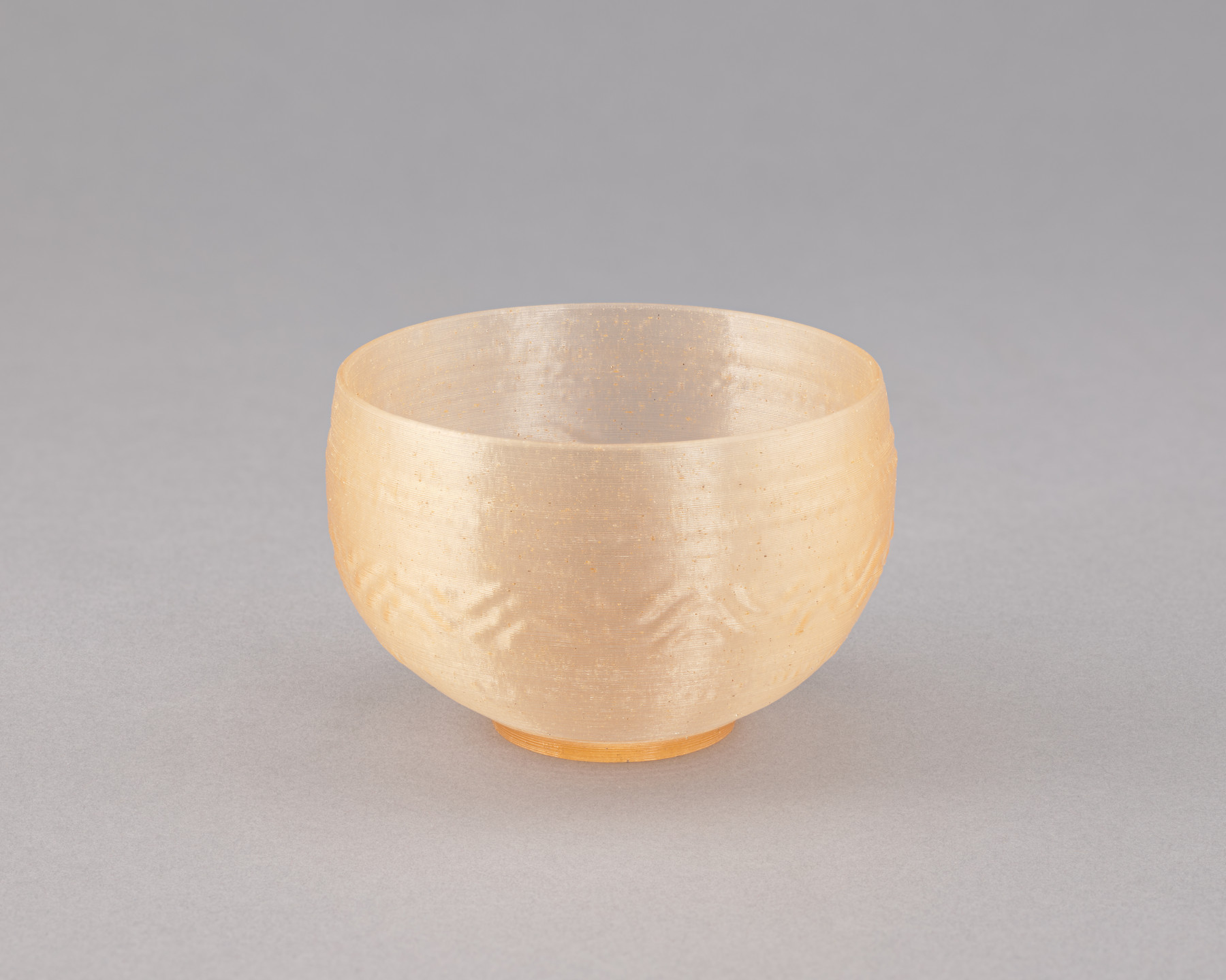 A pale golden-yellow translucent bowl with a smooth, slightly textured surface is centered against a light gray background. The bowl has a rounded shape with a small base. This is an AI generated description. To give feedback, email ai@moma.org.