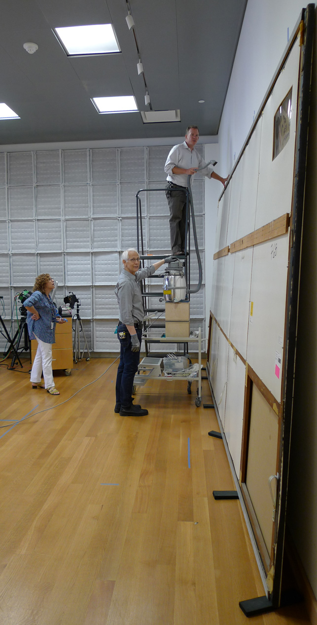 Paintings conservator Michael Duffy, on ladder, removes loose dust from the top edge of One: Number 31, 1950, and the first panels of the painting’s protective backing are removed Paintings conservator Michael Duffy, on ladder, removes loose dust from the top edge of One: Number 31, 1950, and the first panels of the painting’s protective backing are removed