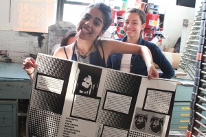 Alya and Stephanie posing with an unfolded zine. 